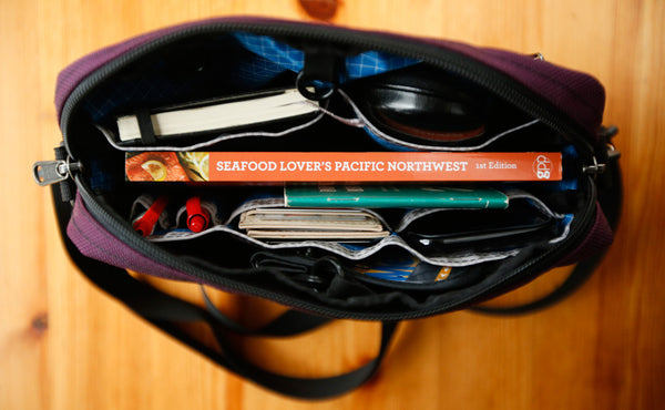 A full Side Kick with a couple books, a pocket notepad, pens,  a phone, stamps, and a wallet.